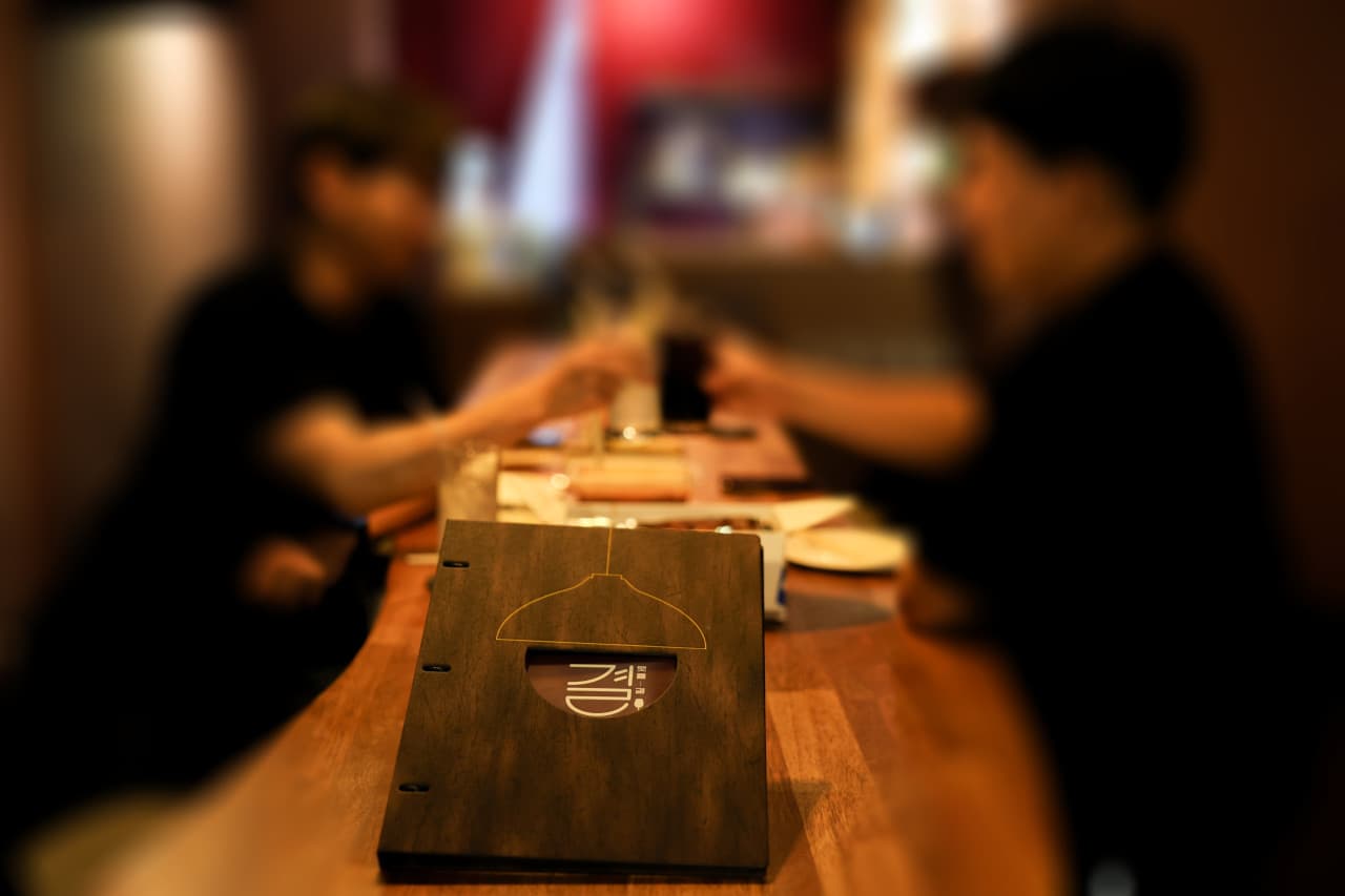 대구광역시 중구 혼술바 결의 나무 카운터 다찌석 위 로고 메뉴판. 낮은 조명 아래 술잔을 든 사람들이 앉아 있는 1인 중심 바(Bar)의 실내 상황.