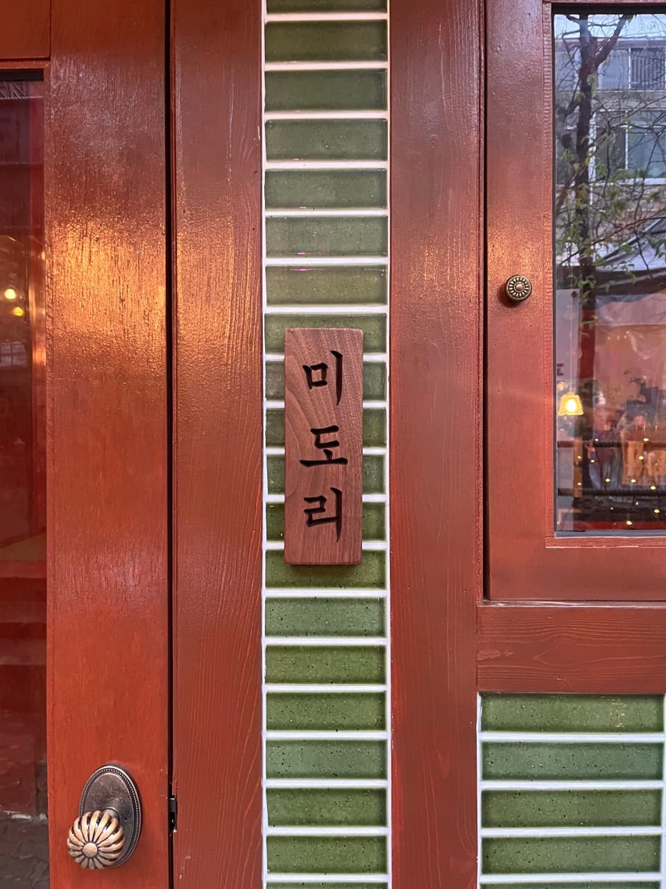 대구광역시 중구 이자카야 미도리 - 원목 문과 초록색 타일 외관 너머 실내 조명과 1인 다찌석이 배치된 모습. 혼술 손님을 위한 정갈한 분위기의 공간 전경.