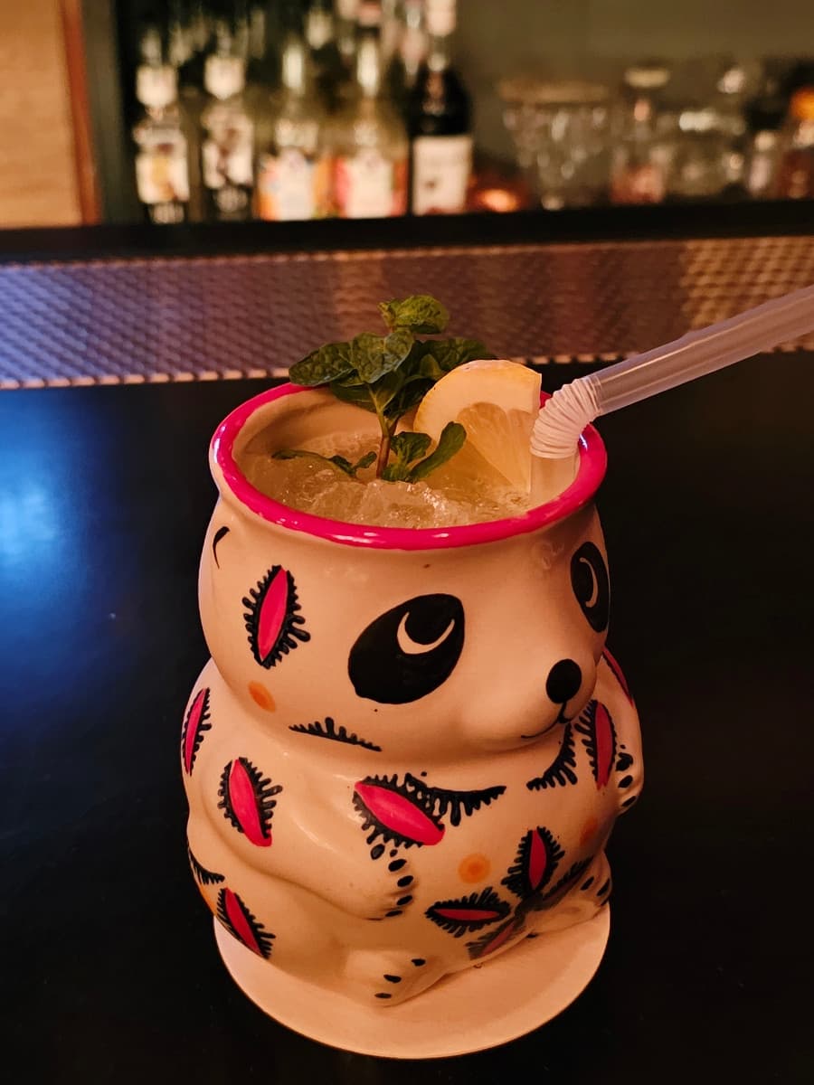 전남광주통합특별시 순천시 더클래식 전남 바(Bar) 다찌석에 놓인 판다 머그 칵테일. 어두운 조명 아래 민트와 레몬이 곁들여진 음료가 배치된 1인 혼술 상황을 묘사함.