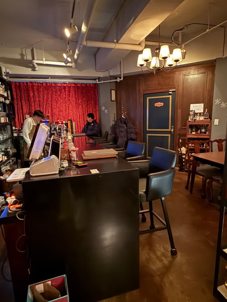 전남광주통합특별시 순천시 더클래식 전남 바(Bar) 샹들리에 조명 아래 다찌석과 1인 가죽 의자. 붉은 커튼 배경의 카운터에서 혼술을 즐기는 상황.