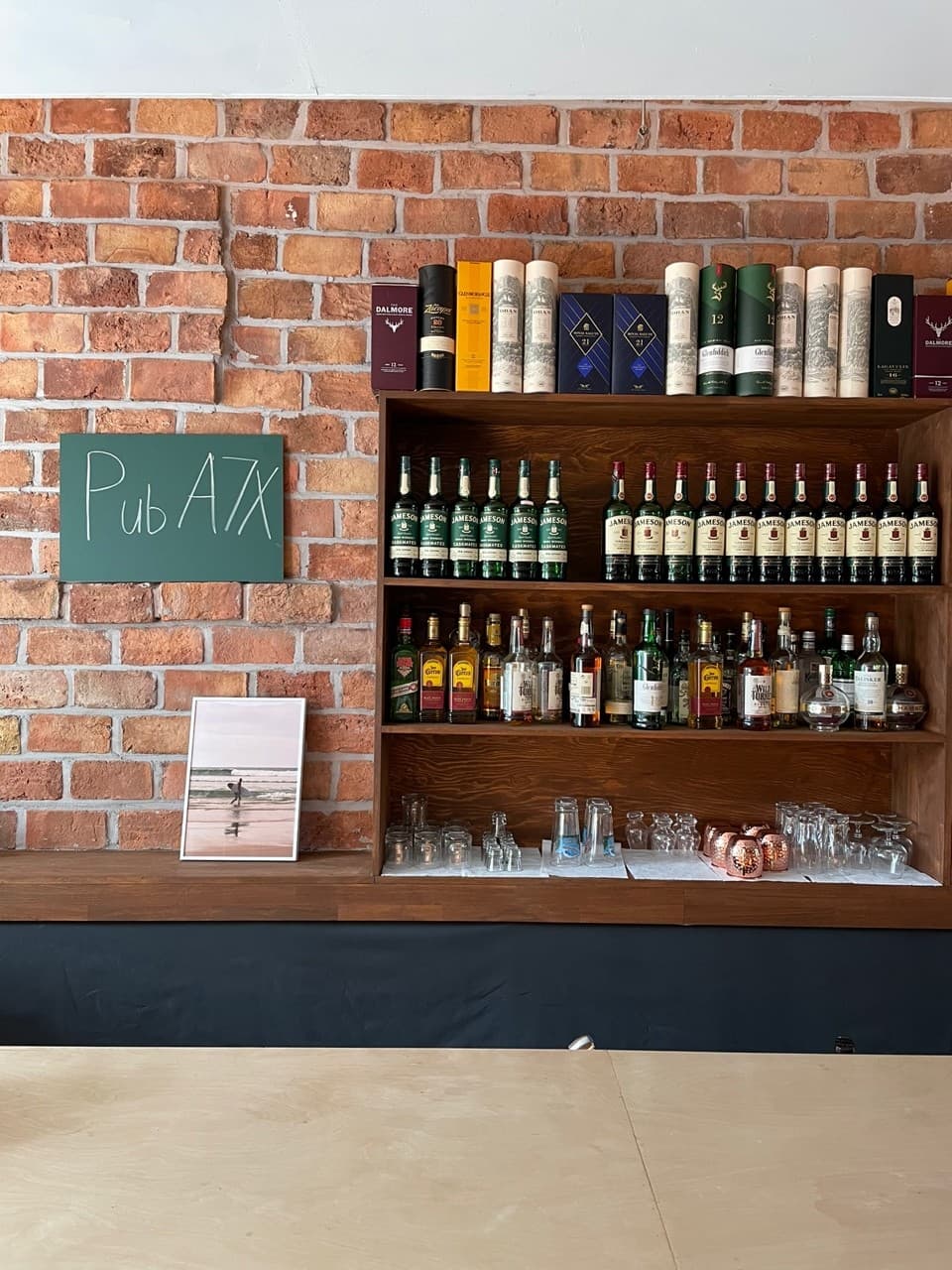 인천광역시 남동구 혼술 바(Bar) A7X 인천 - 붉은 벽돌 벽과 위스키가 진열된 나무 선반, 원목 다찌석 카운터가 배치된 1인 좌석 공간