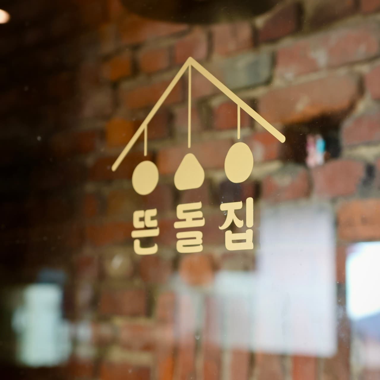 인천광역시 제물포구 요리주점 뜬돌집 인천 유리창 로고와 벽돌 배경. 다찌석 은은한 조명 아래 1인 혼술 메뉴와 식재료 질감이 드러나는 상차림 및 내부 전경.