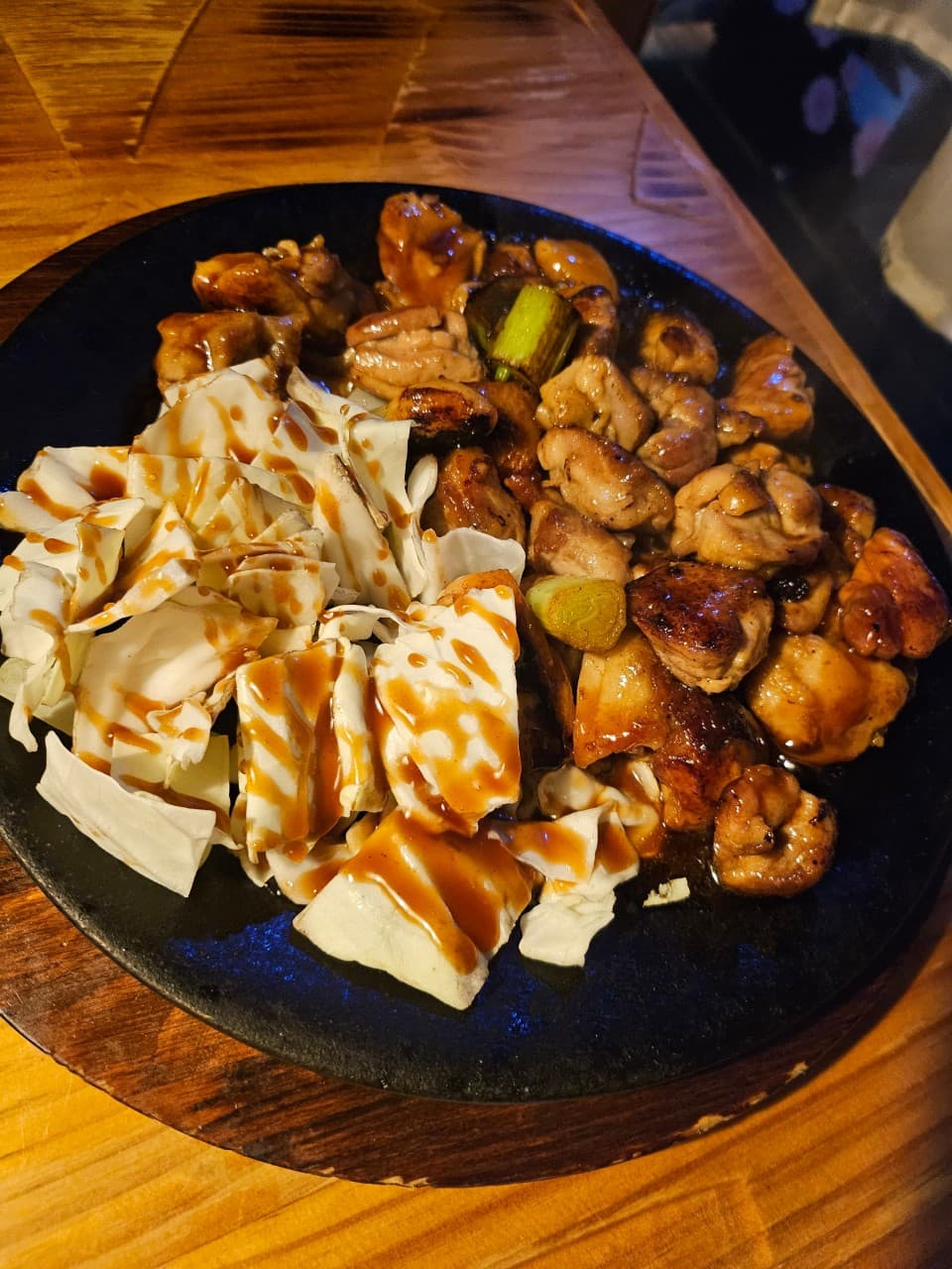 인천광역시 부평구 이자카야 코코스키 부평점 인천 1인 다찌석. 조명 아래 윤기 도는 닭구이와 소스가 뿌려진 양배추의 질감이 돋보이는 혼술 메뉴.