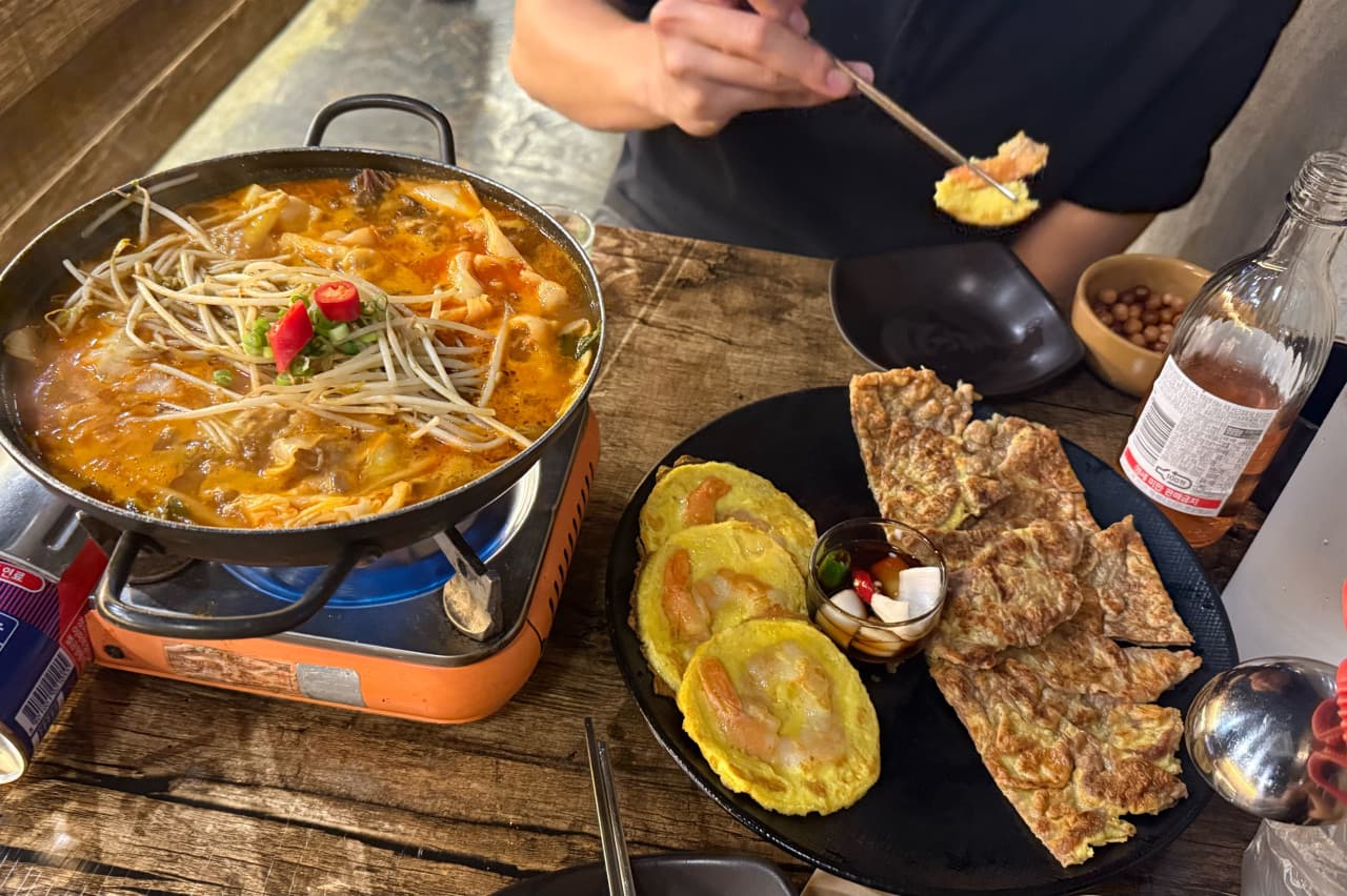 인천광역시 연수구 요리주점 만취로 송도트리플점 인천 다찌석에서 혼술로 즐기는 얼큰한 전골과 육전. 가스레인지 위 끓는 국물과 노릇한 전의 질감이 조명 아래 보이는 상황.