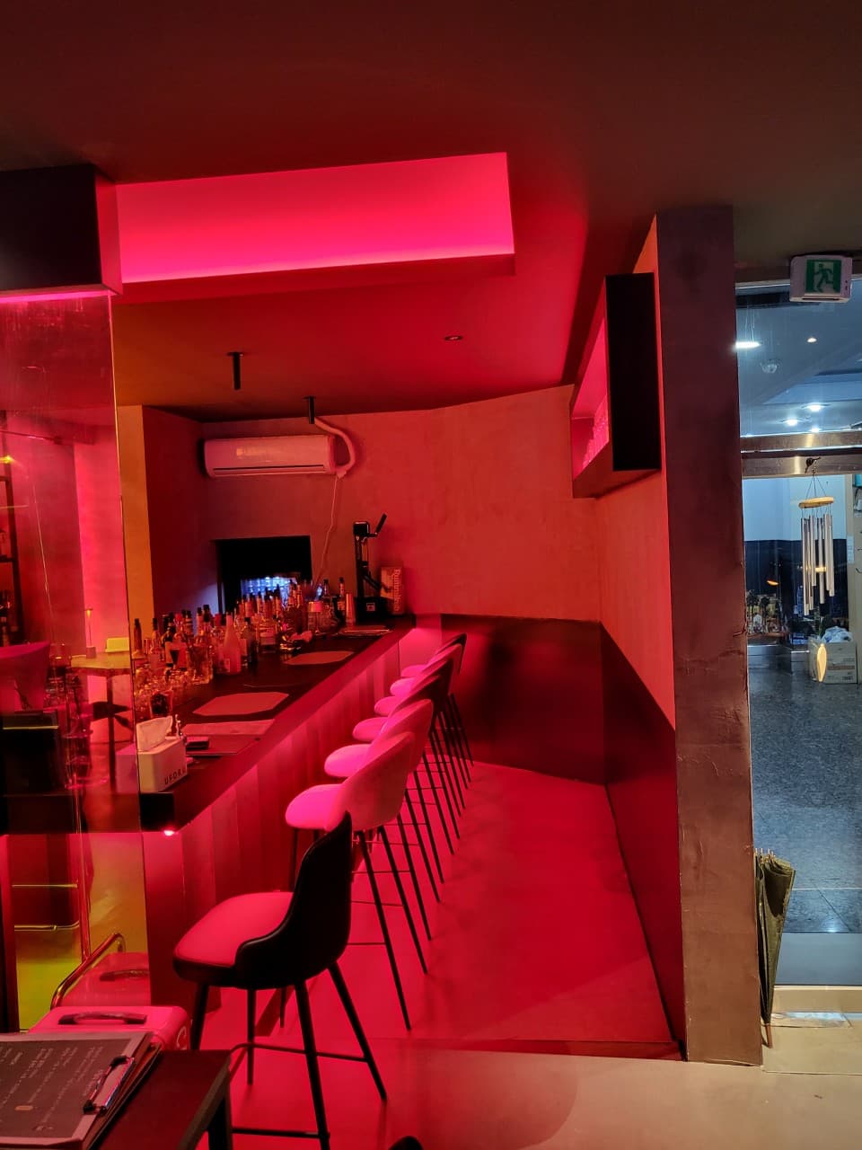 인천광역시 미추홀구 레이브 인천 바(Bar)의 붉은 네온 조명이 비치는 긴 카운터 다찌석과 1인용 높은 의자가 배치된 혼술 공간