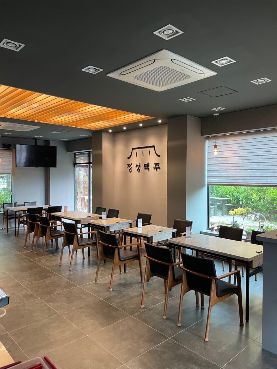 인천광역시 연수구 정성맥주 인천 맥주 호프. 천장 매립등 아래 대리석 테이블과 검은 의자가 배치된 혼술 가능한 1인 좌석과 정돈된 매장 내부 전경