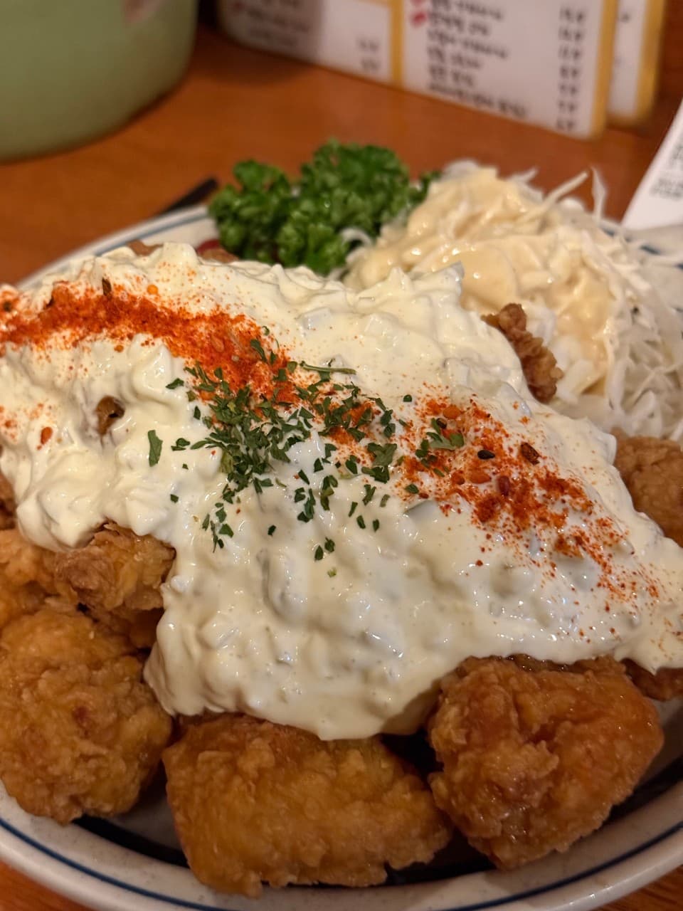 인천광역시 미추홀구 야키토리 니센 인천 이자카야 다찌석 혼술. 노란 조명 아래 타르타르 소스, 파슬리, 파프리카 가루를 얹은 바삭한 치킨 가라아게가 목재 테이블에 차려짐.