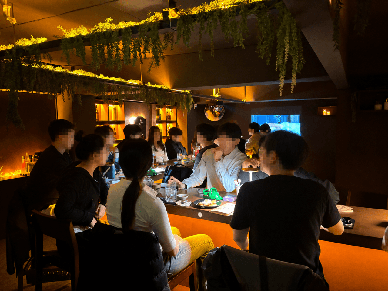 전남광주통합특별시 순천시 야화 혼술바 순천점 바(Bar) - 주황색 조명과 식물 장식 아래 1인 다찌석에 앉아 술잔과 안주를 앞에 둔 상황