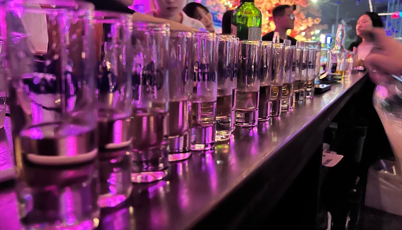 서울특별시 마포구 호랑이 라운지 서울 바(Bar)의 보라색 조명이 비치는 다찌석에 일렬로 배치된 투명한 샷잔들. 혼술을 위한 1인 카운터석 테이블 전경.