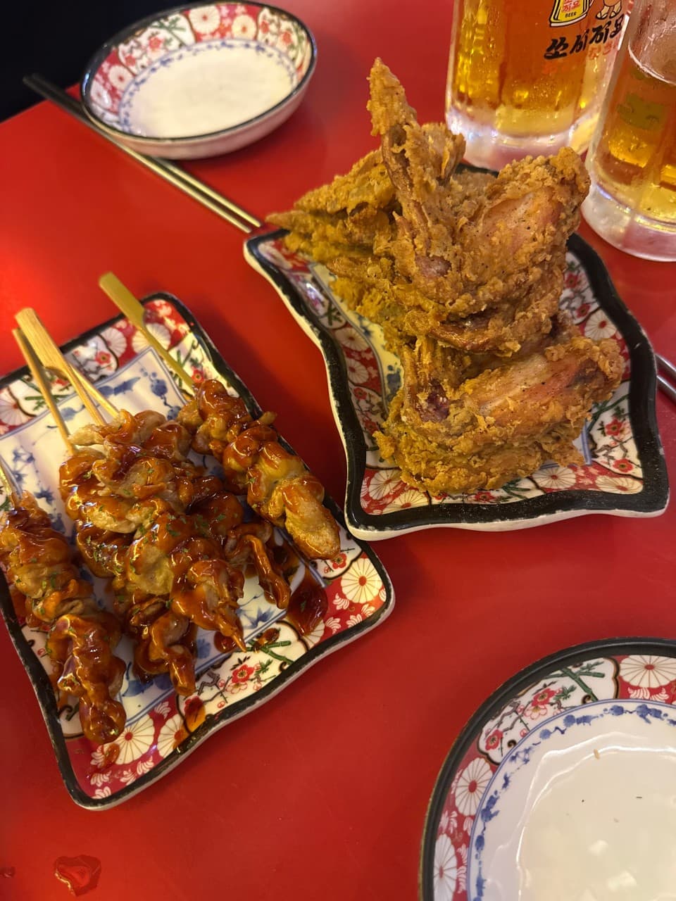 세종특별자치시 나성로 쏘시지요 세종나성점 이자카야 다찌석에서 즐기는 혼술. 붉은 테이블 위 바삭한 튀김과 소스 입힌 꼬치, 시원한 생맥주가 차려진 1인 상차림.