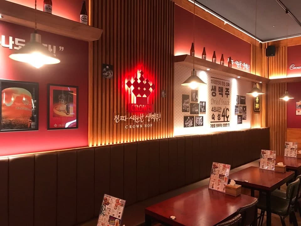 세종특별자치시 마음안1로 크라운호프 세종고운점 맥주 호프 내부. 붉은 조명과 나무 칸막이가 있는 벽면 소파 좌석의 혼술 공간. 숙성 생맥주 문구와 테이블 위 메뉴판이 배치된 매장 전경.