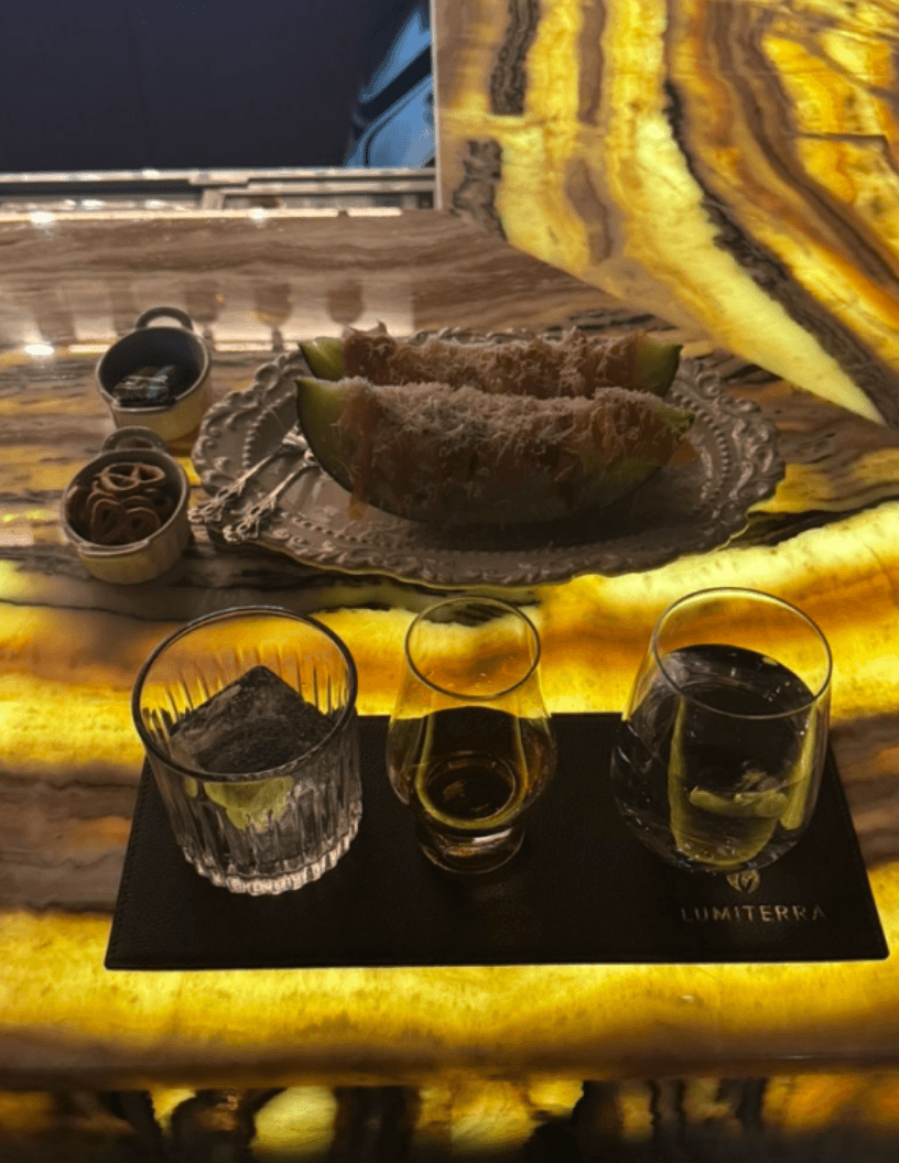 대전광역시 유성구 루미테라 대전 바(Bar) - 황금빛 조명이 투과되는 다찌석 위 치즈가 뿌려진 멜론 하몽과 1인 혼술용 위스키 온더락 세트
