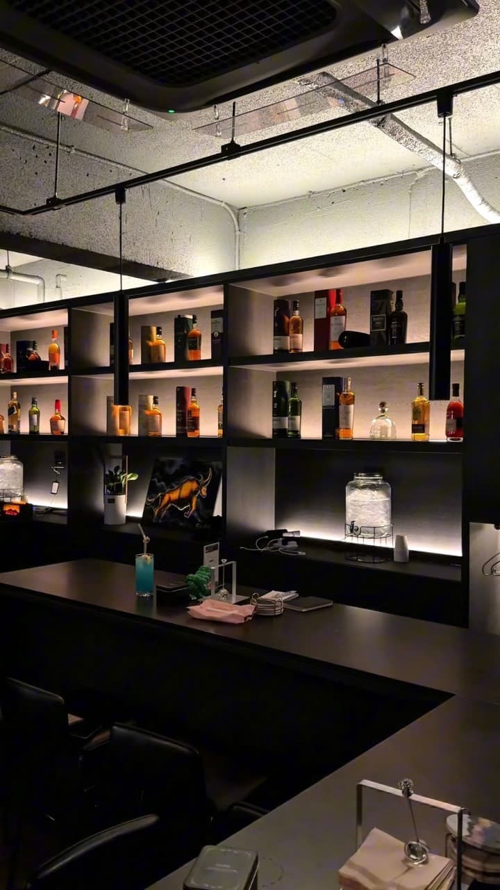 인천광역시 부평구 꼼바혼술바 인천부평점 인천 바(Bar). 주류 진열장 조명이 비치는 1인 다찌석과 카운터 위 푸른색 칵테일이 배치된 혼술 상황.
