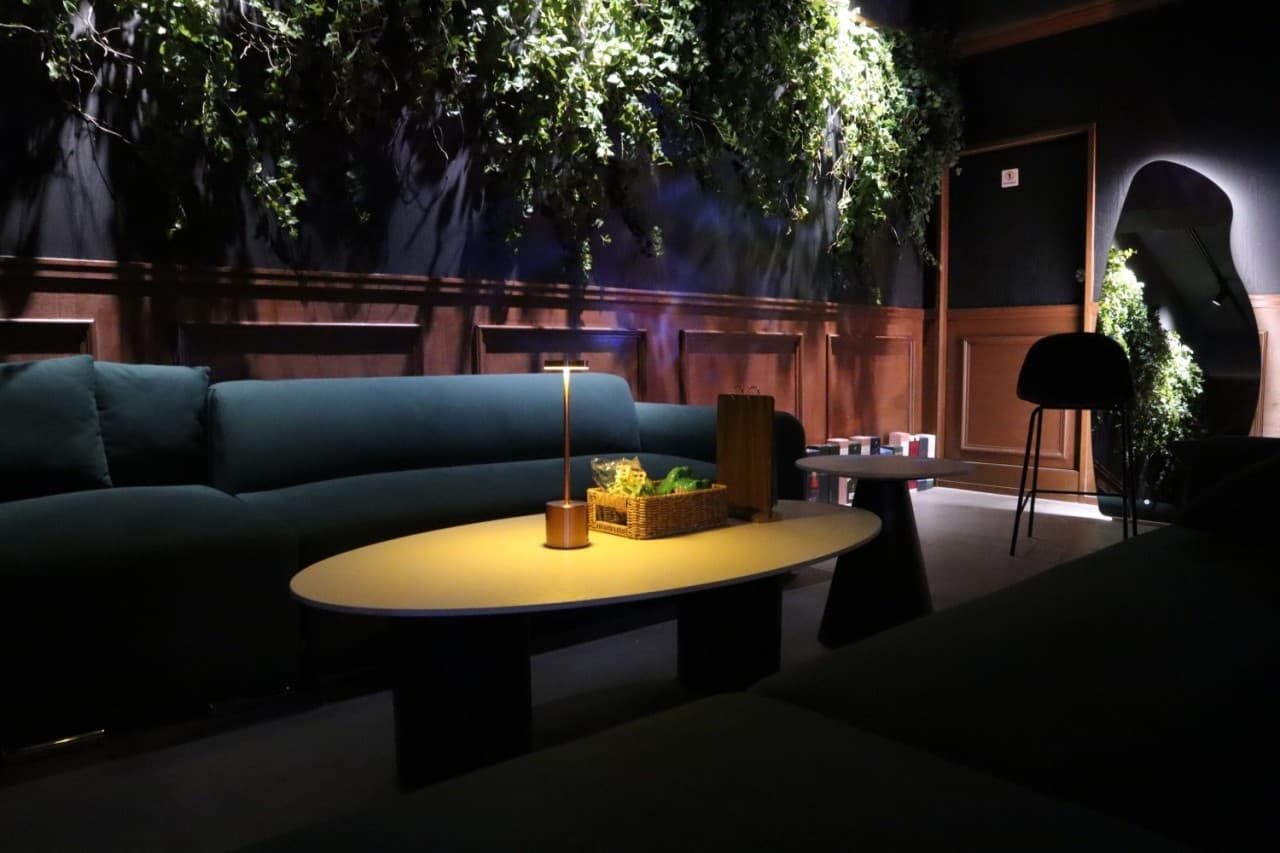 인천광역시 부평구 혼술바 고도 부평점 인천 바(Bar). 핀 조명 아래 초록색 소파와 낮은 테이블, 바구니 속 신선한 채소. 넝쿨 식물과 거울이 배치된 1인 혼술 전용 좌석.