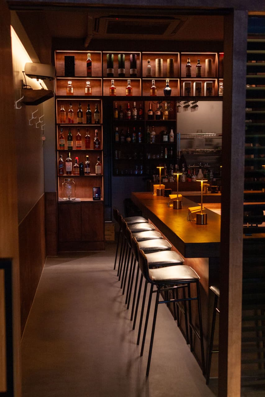 인천광역시 남동구 혼술바 또랑 인천 바(Bar) - 은은한 조명 아래 일렬로 놓인 1인 다찌석과 벽면 선반을 채운 위스키병들이 보이는 조용한 혼술 공간