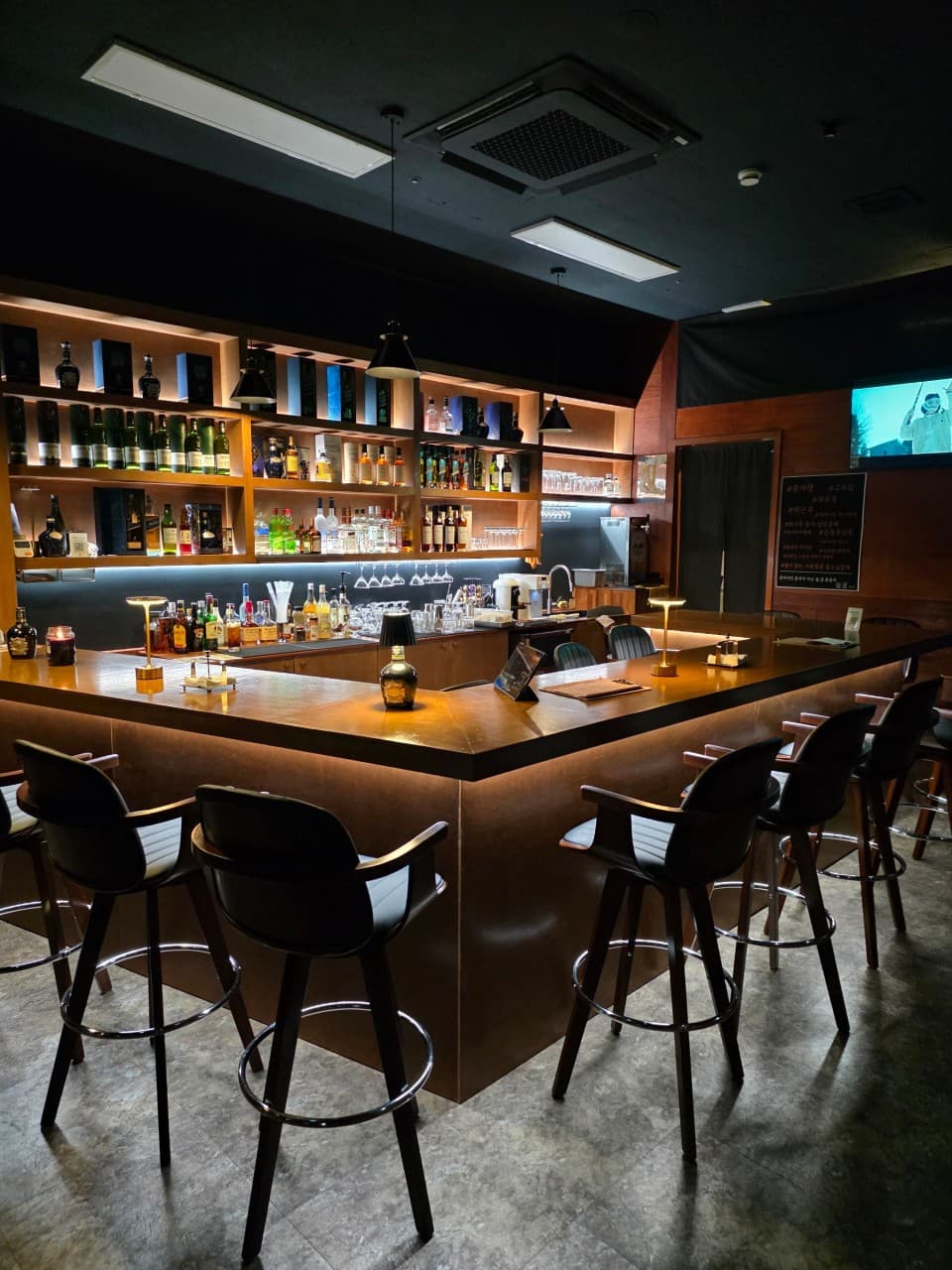 전남광주통합특별시 목포시 술결 목포혼술바 전남 바(Bar)의 주황색 조명 아래 나무 소재 다찌석과 1인용 바 의자가 정렬된 혼술 전용 공간