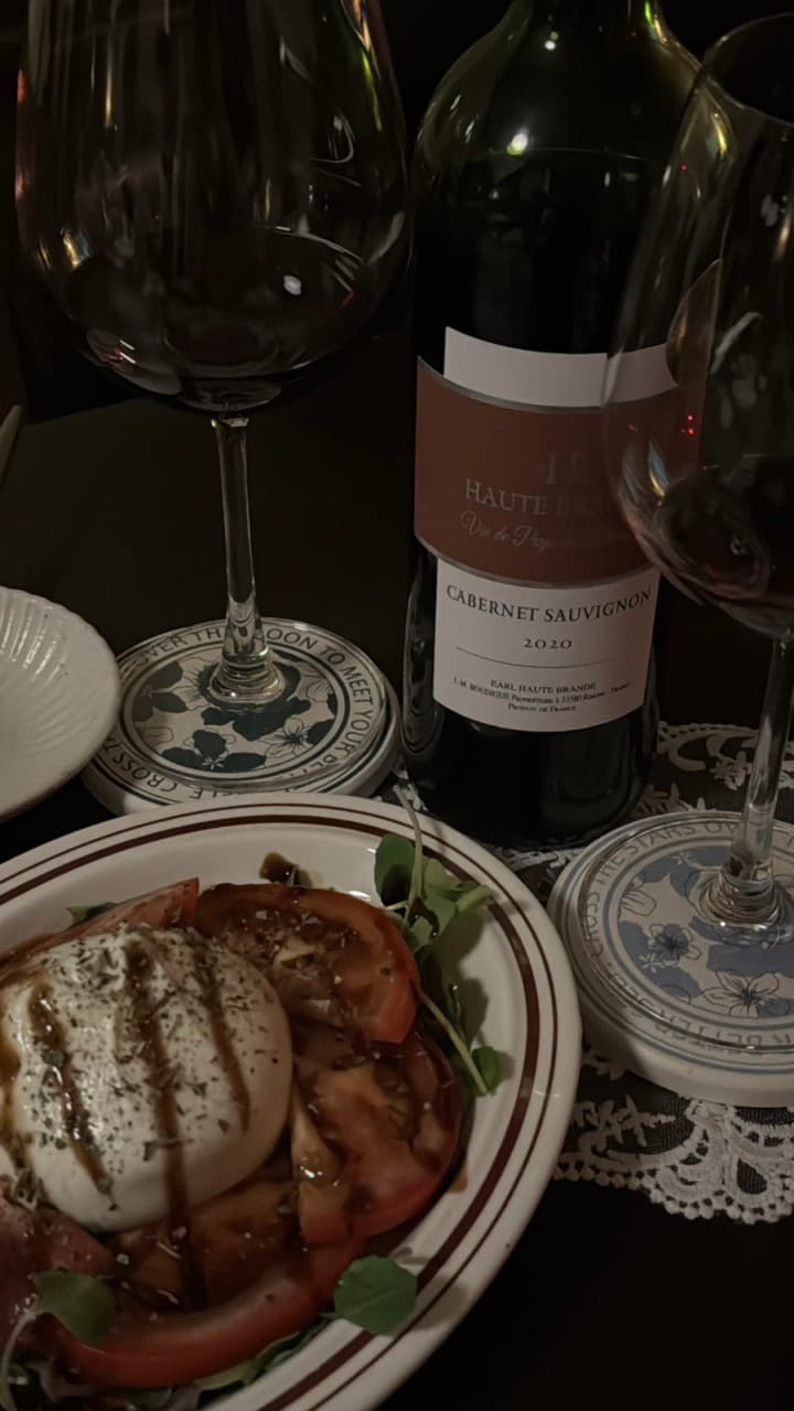 전남광주통합특별시 순천시 은재 전남 바(Bar) 어두운 조명 아래 다찌석에 차려진 토마토 부라타 치즈 샐러드와 레드 와인 1인 혼술 상차림