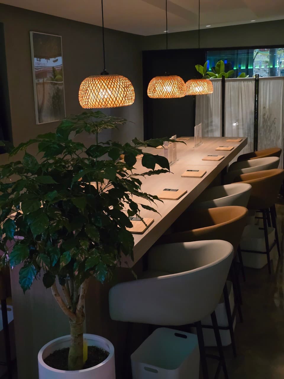 전남광주통합특별시 동구 혼술바 우리의언어 전남 - 라탄 조명 아래 1인 다찌석과 정갈한 매트가 놓인 원목 테이블이 있는 바(Bar) 실내