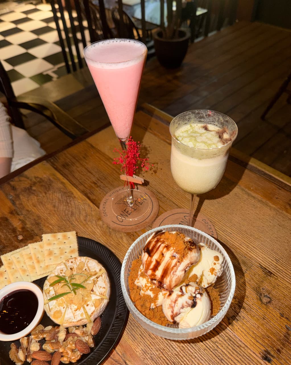 전남광주통합특별시 동구 원텐 전남 바(Bar) 나무 테이블 위 핑크 칵테일과 아이스크림. 체크무늬 바닥이 보이는 공간에서 크래커와 치즈 안주로 즐기는 1인 혼술 상황임.
