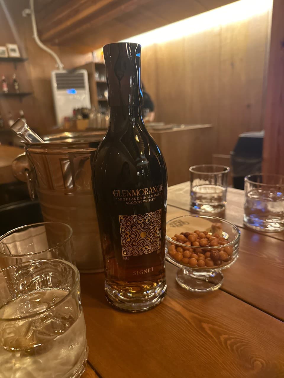 경상북도 경주시 연한밤 혼술바 경북 바(Bar) 다찌석에 놓인 글렌모란지 시그넷 위스키와 견과류 안주. 조명 아래 나무 카운터에서 즐기는 1인 혼술 상황