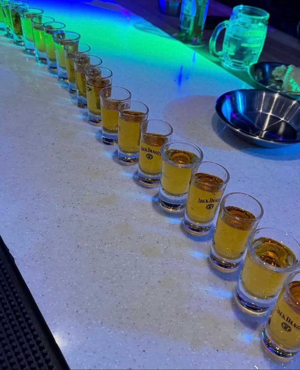 경상북도 포항시 이스트사이드뮤직 경북 바(Bar) 푸른 네온 조명 아래 카운터석에 일렬로 늘어선 위스키 샷잔들. 다찌석에서 혼술을 즐기는 상황과 금속 식기.