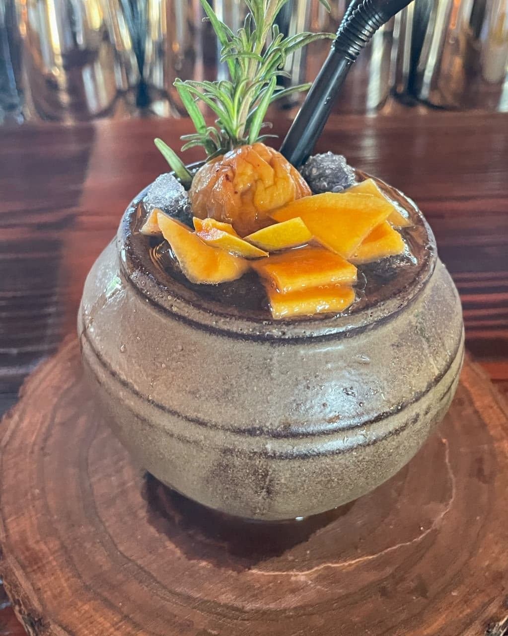 경상북도 경주시 바분 월정교점 경북 바(Bar) 다찌석 혼술. 항아리 잔에 담긴 말린 과일과 허브 토핑 칵테일이 나무 코스터와 목재 테이블 위에 놓임.