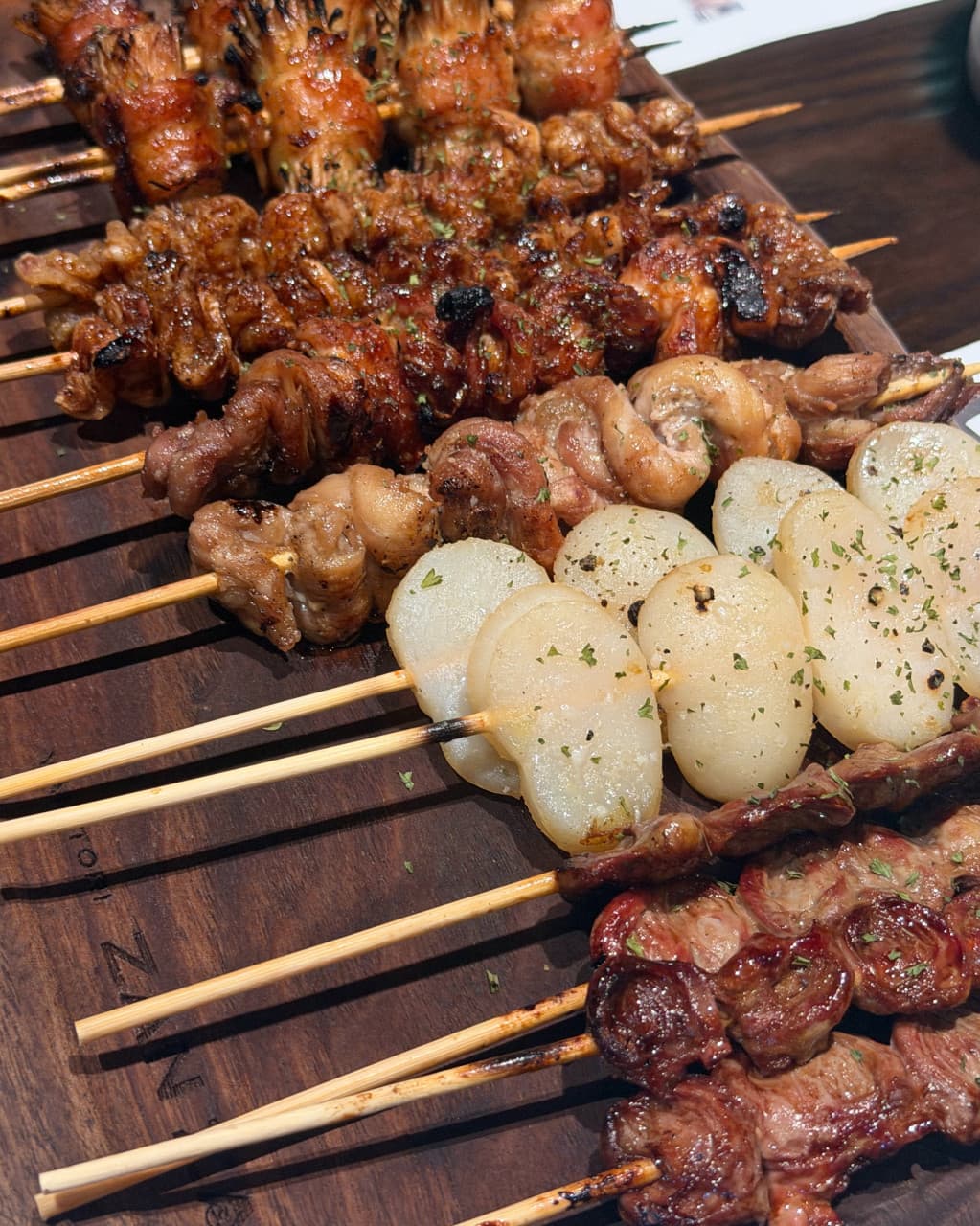 경기도 양주시 이자카야 야키토리잔잔 양주옥정점 경기 1인 다찌석 혼술. 조명 아래 노릇하게 구운 닭꼬치와 마늘의 질감이 돋보이는 정갈한 상차림.