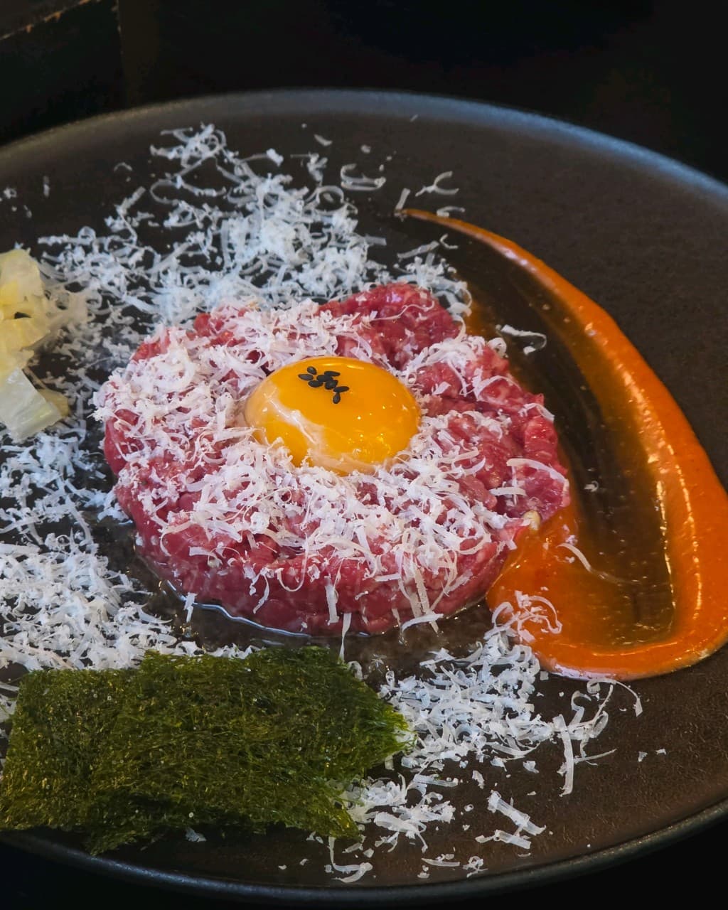 경기도 수원시 요리주점 쌀술집 경기 다찌석에서 즐기는 혼술. 계란 노른자와 치즈 가루를 얹은 육회와 감태가 어두운 조명 아래 차려진 1인 메뉴.