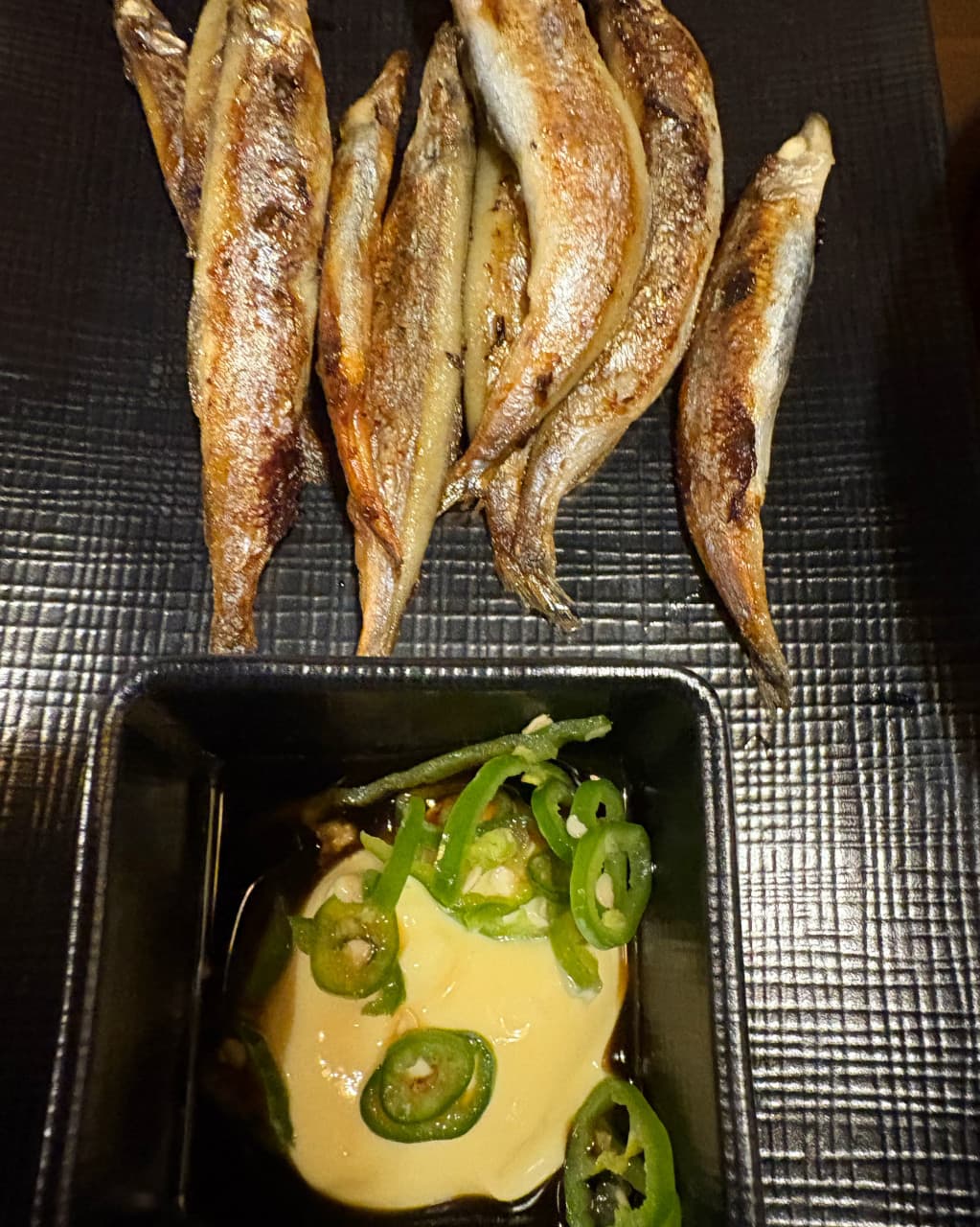 경기도 부천시 철판오사카야 부천점 경기 이자카야 다찌석 조명 아래 놓인 시샤모 구이와 고추 마요네즈. 1인 혼술 차림의 생선 질감과 소스의 구성이 드러남.