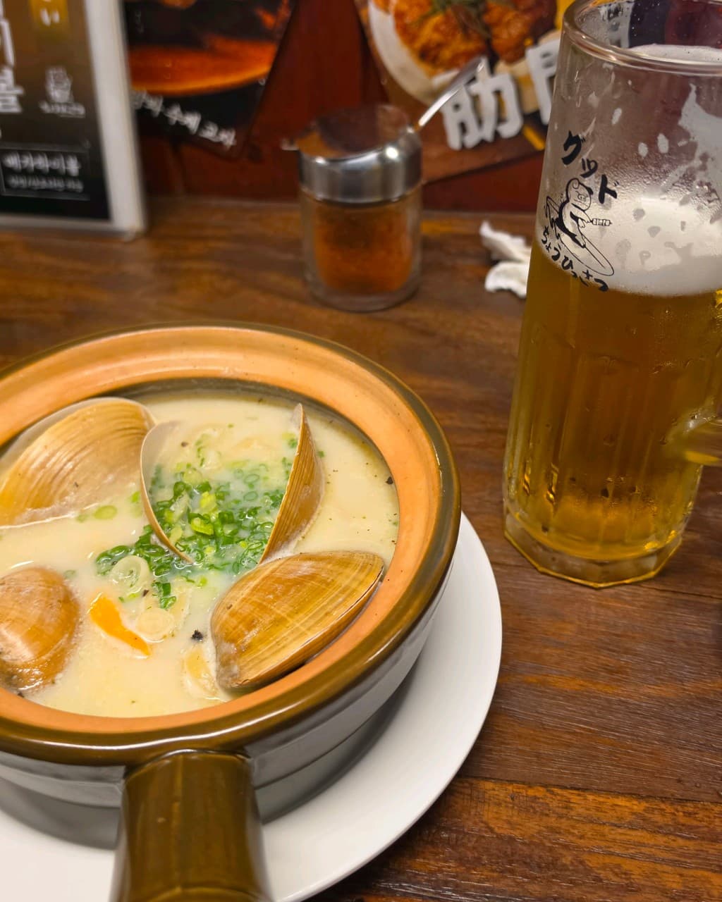 부산광역시 수영구 이자카야 초힛사츠 부산 다찌석에서 즐기는 1인 혼술. 나무 테이블 위 뽀얀 국물의 조개탕과 기포가 서린 생맥주가 놓인 상황.