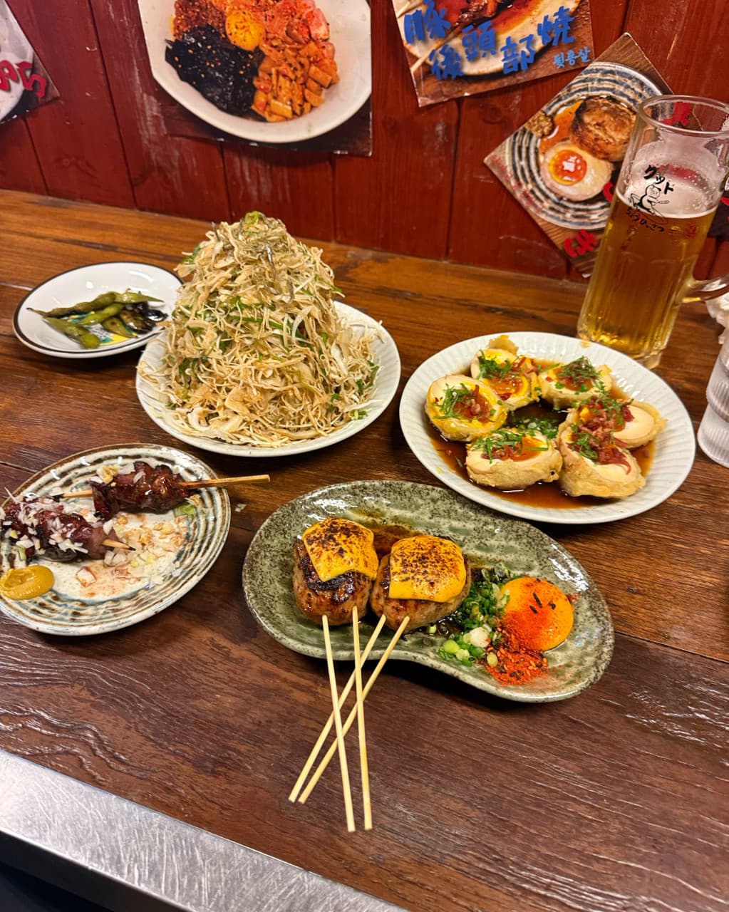 부산광역시 수영구 초힛사츠 부산 이자카야 - 나무 다찌석 위 1인 혼술을 위한 치즈 츠쿠네와 산더미 양배추, 생맥주가 조명 아래 차려진 상황