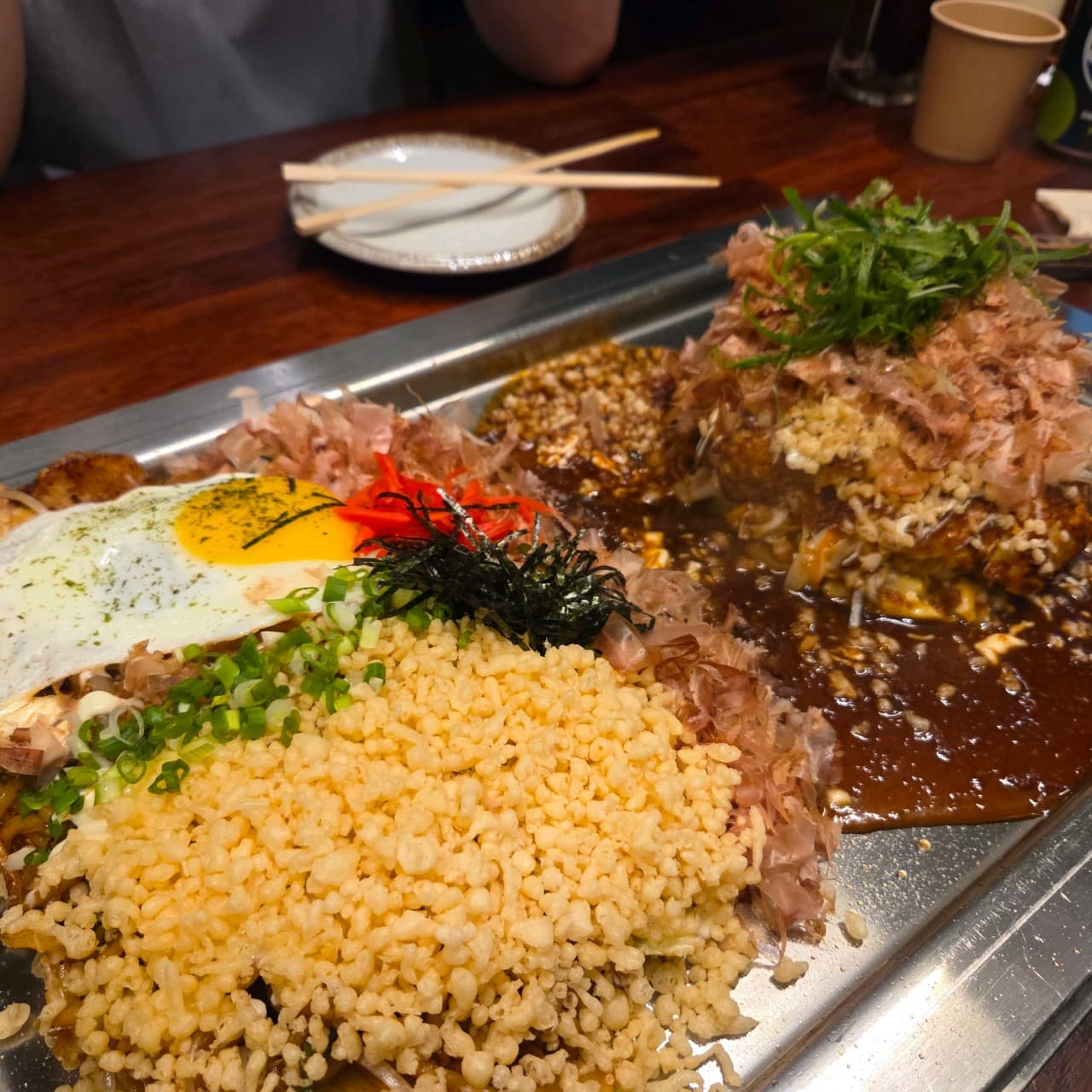 부산광역시 부산진구 야키야 본점 부산 이자카야 다찌석 혼술. 조명 아래 철판 위 반숙 계란과 가쓰오부시가 듬뿍 올라간 오코노미야키의 바삭한 질감과 식기.
