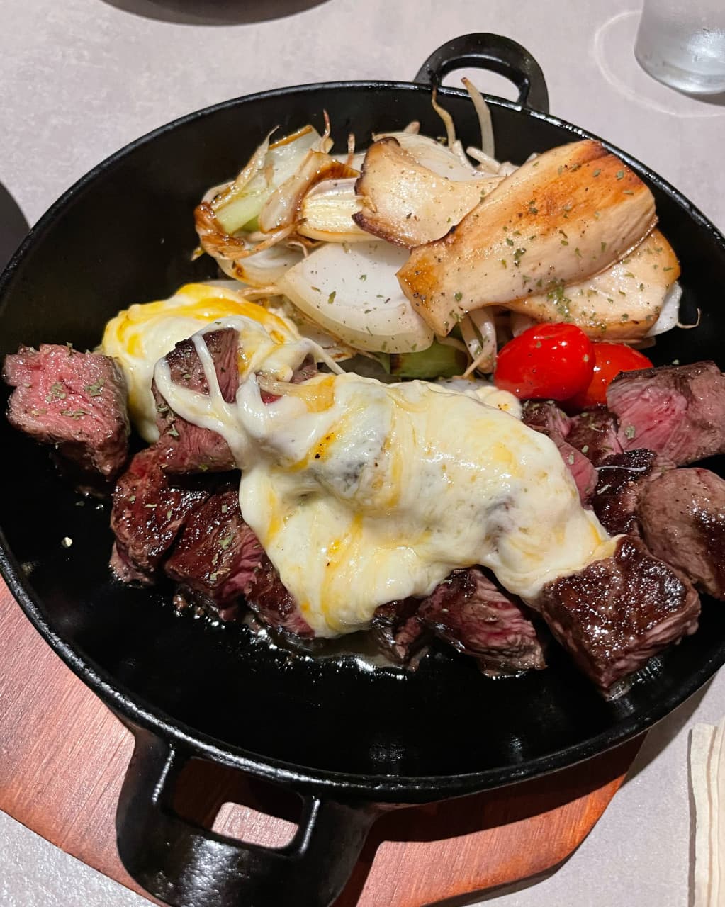 부산광역시 부산진구 그린애플 전포점 부산 요리주점 다찌석 조명 아래 녹아내린 치즈를 얹은 1인 소고기 스테이크와 구운 채소. 혼술 구성의 검은 무쇠 팬 차림.