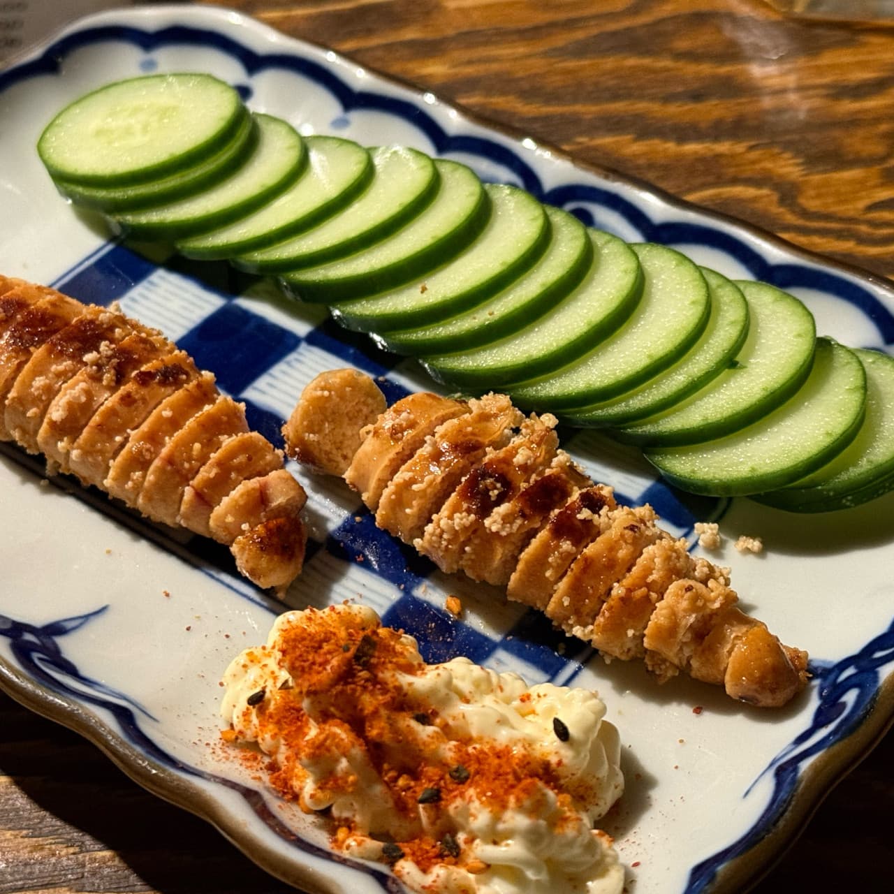 대구광역시 중구 요로이케 교동점 이자카야 다찌석에 차려진 명란구이와 오이. 조명을 받는 1인 혼술 안주와 마요네즈 소스가 놓인 나무 테이블 상단.