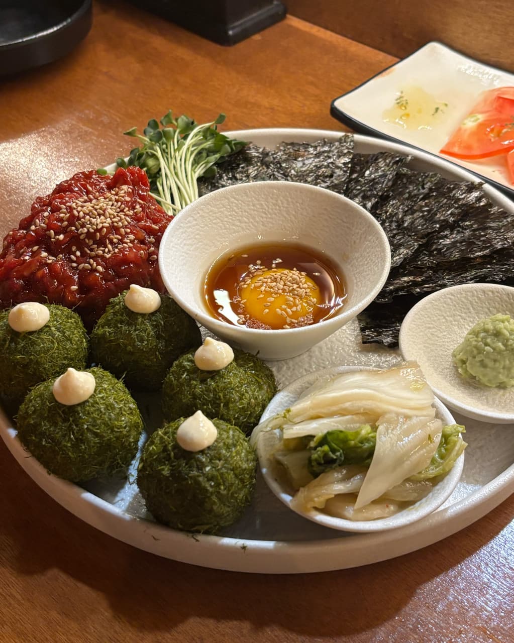 부산광역시 동래구 요리주점 월하주방 부산 다찌석에 차려진 1인 육회와 감태 주먹밥 세트. 노란 조명 아래 김과 노른자 소스가 놓인 나무 테이블 위 상차림.