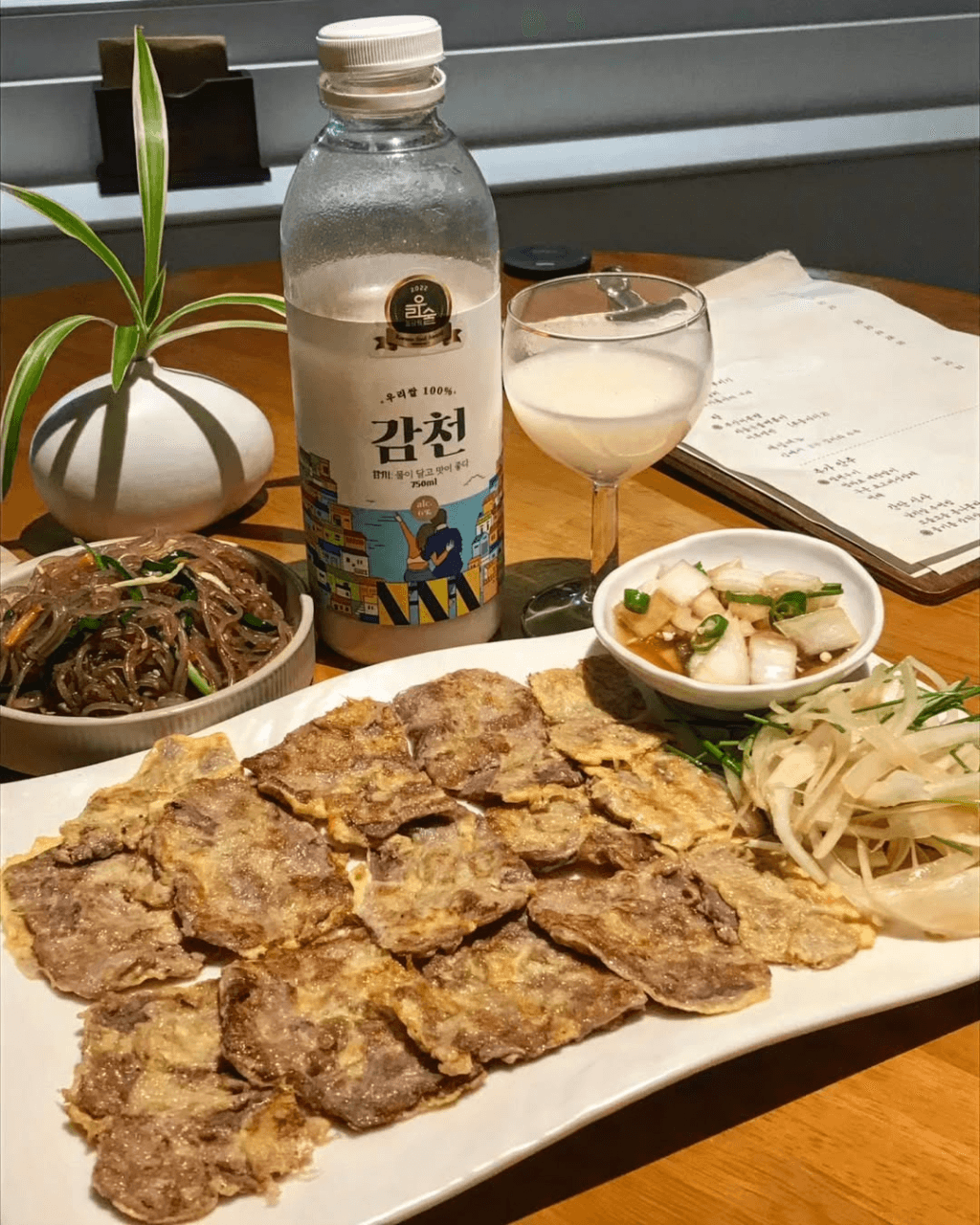 부산광역시 수영구 요리주점 광안야행 부산의 다찌석 혼술 차림. 노란 조명 아래 노릇한 육전과 잡채, 막걸리가 놓인 1인 테이블의 시각적 분위기.