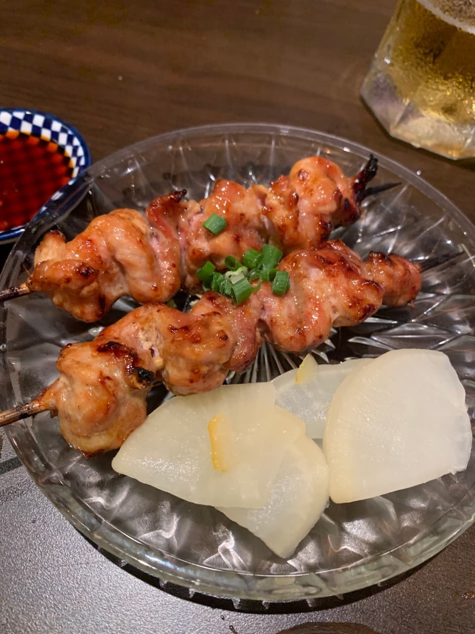 인천광역시 남동구 이자카야 야키토리동작 인천시청점 다찌석 조명 아래 놓인 닭꼬치와 단무지. 투명한 접시에 담긴 고기 질감과 맥주가 있는 1인 혼술 상황.