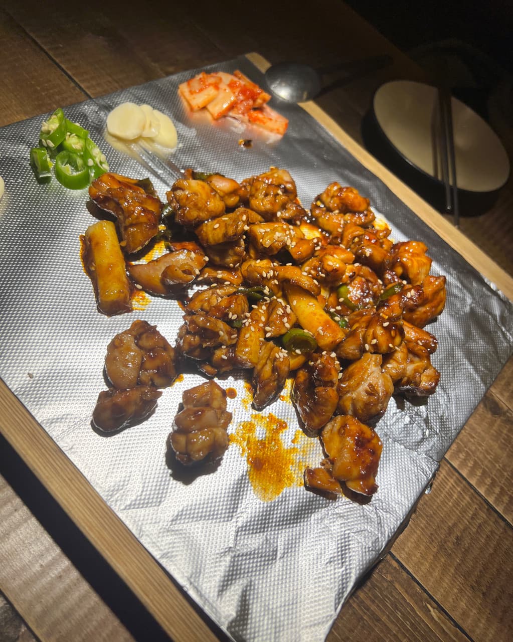 인천광역시 남동구 요리주점 한식주점낭만 구월점 인천 다찌석 1인 혼술 상황. 은박지 위 윤기 흐르는 양념 고기 볶음과 떡, 마늘, 고추가 차려진 모습