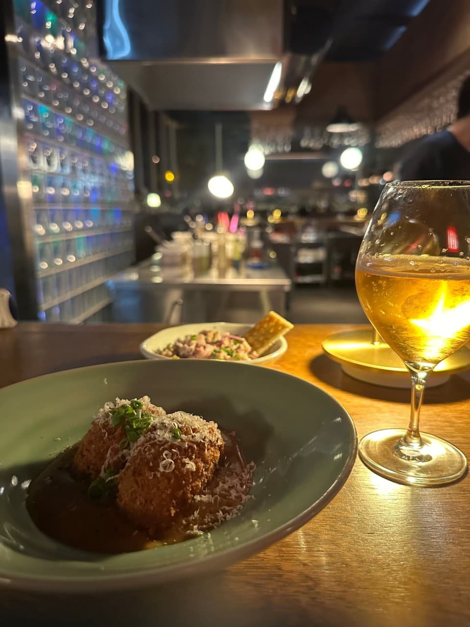 제주특별자치도 제주시 불특정식당 제주 와인 바 다찌석 혼술. 조명 아래 치즈 가루가 뿌려진 튀김 요리와 와인 잔이 차려진 목재 테이블과 유리 블록 배경.