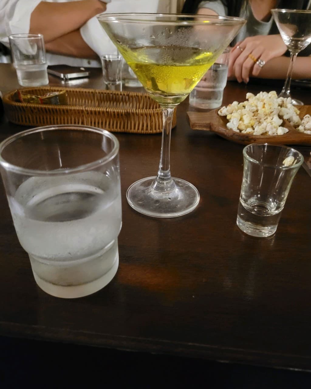 제주특별자치도 제주시 또똣 제주혼술바 바(Bar) 다찌석에 놓인 노란색 칵테일과 팝콘 안주. 투명한 물잔과 샷잔이 배치된 나무 테이블에서 혼술을 즐기는 상황.