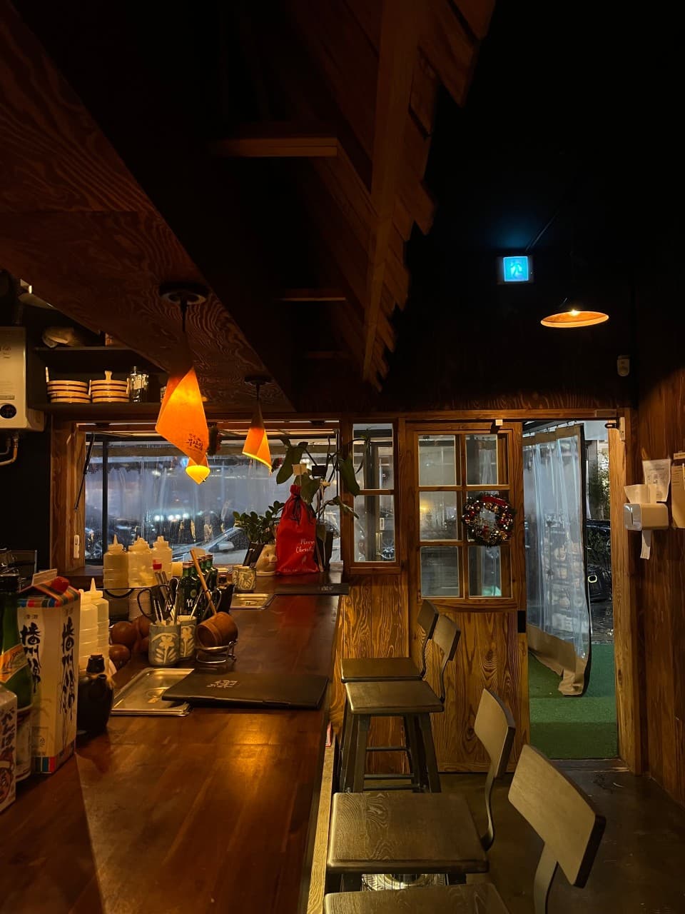 대전광역시 서구 요리주점 철길부산집 대전관저점 내부. 주황빛 조명 아래 긴 나무 소재 다찌석과 1인용 의자. 메뉴판과 식기가 정돈된 카운터 테이블에서 혼술을 즐기는 상황.