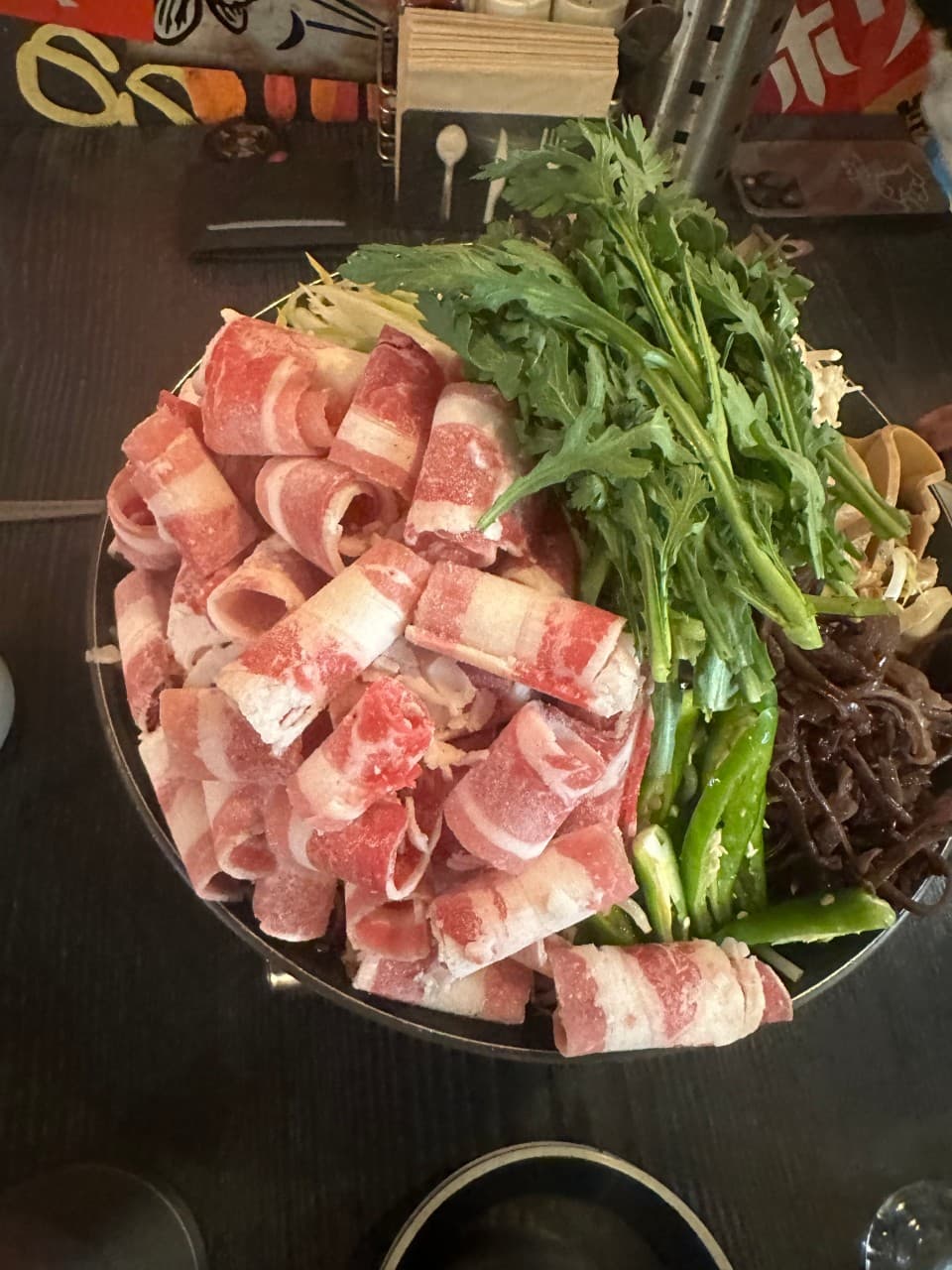 대전광역시 유성구 이자카야 꼬치는밤 대전의 다찌석 혼술 구성. 원목 테이블 위 붉은 차돌박이와 초록색 쑥갓이 쌓인 1인 나베. 어두운 실내 조명 아래 식재료의 질감이 강조된 모습.