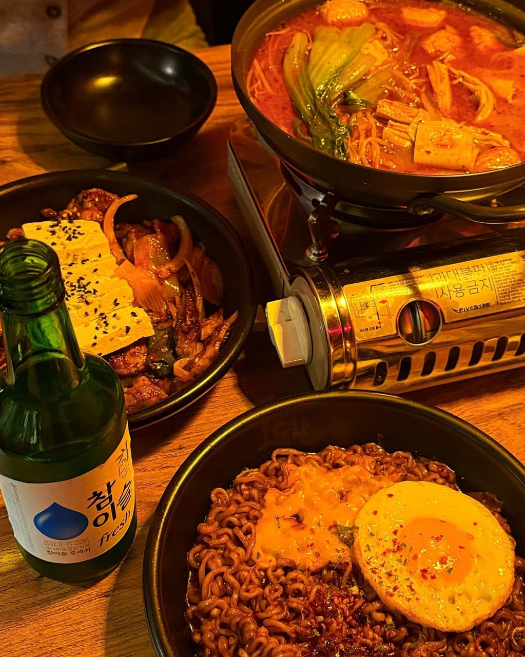 경기도 부천시 오술차 부천역점 경기 요리주점 - 주황색 조명 아래 1인 다찌석에 놓인 매콤한 전골과 두부김치, 계란프라이를 올린 짜장라면과 소주 혼술