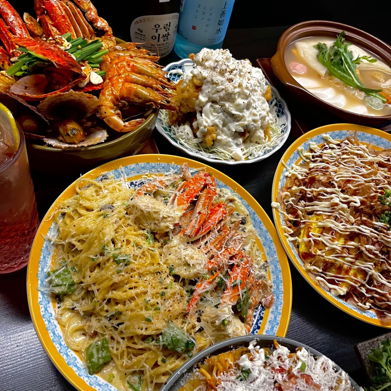 경기도 고양시 이자카야 심야식당 세솔리 경기 - 혼술 다찌석에 차려진 대게 크림 파스타와 해산물 요리. 조명 아래 소스와 가쓰오부시의 질감이 돋보이는 여러 안주와 하이볼이 놓인 1인 테이블.