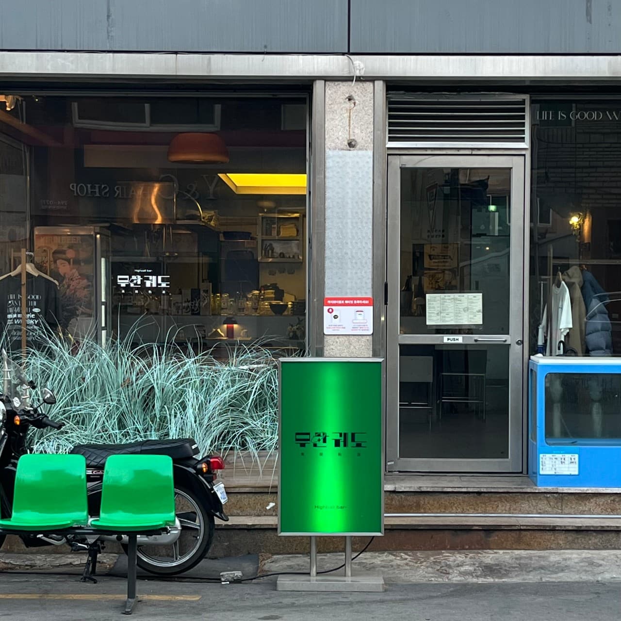 대구광역시 중구 삼덕동 무한궤도 대구 - 초록색 입간판과 의자 너머 노란 조명이 비치는 다찌석 내부. 혼술 가능한 1인석 중심의 공간 구성.