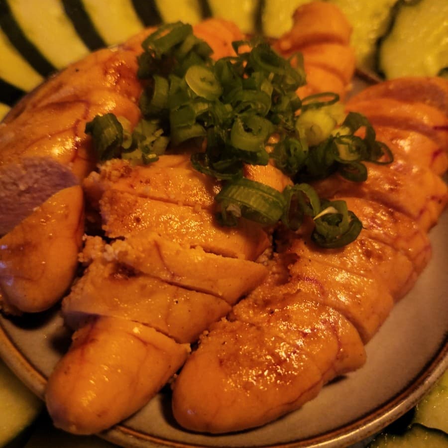 대구광역시 중구 요바나시 대구종로점 이자카야 다찌석 조명 아래 놓인 명란구이와 오이. 1인 혼술 안주의 알갱이 질감과 송송 썬 쪽파가 차려진 모습.