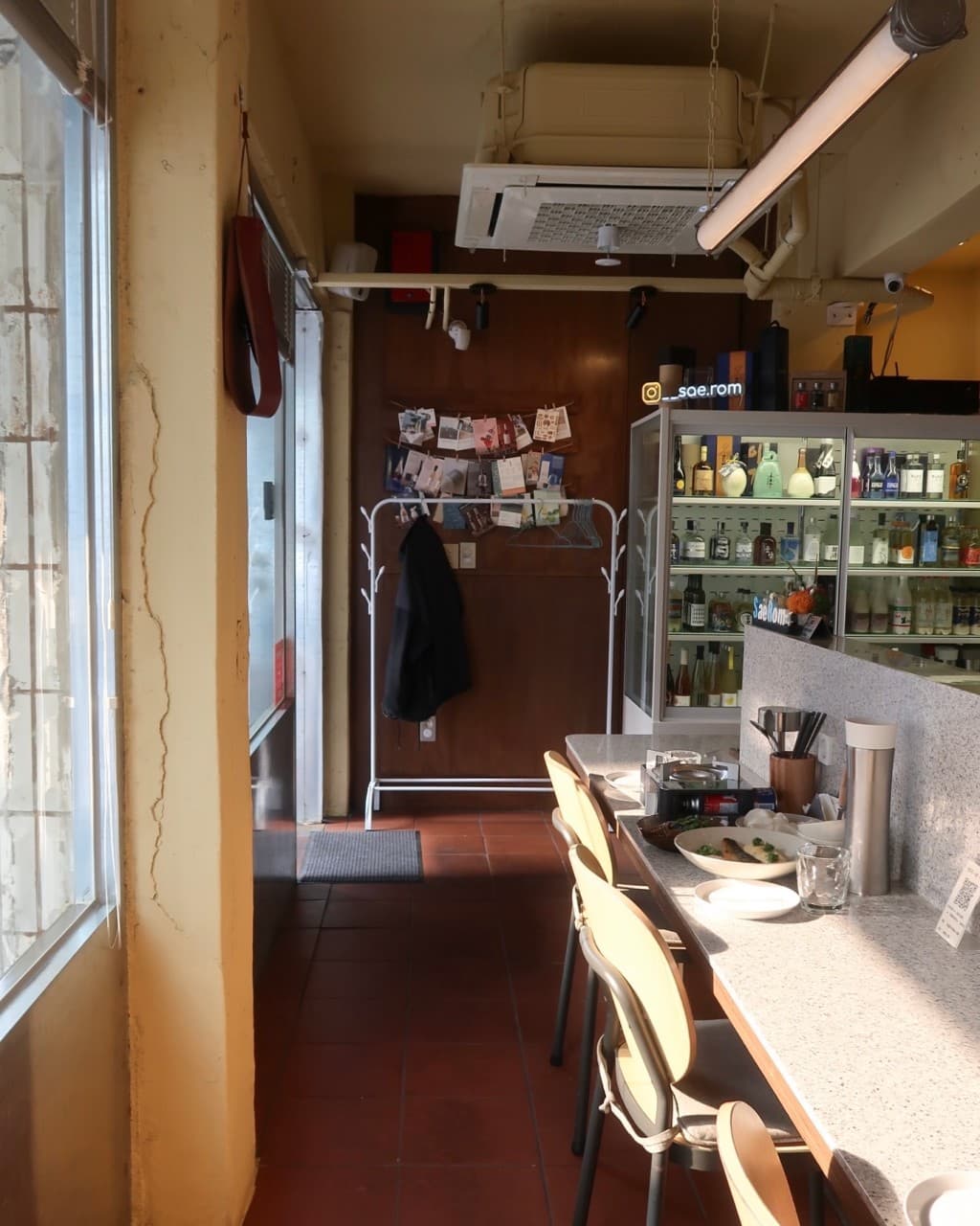대구광역시 수성구 한식주점 새롬 대구 요리주점의 창가 다찌석. 윤기 흐르는 1인 요리와 식기류가 놓인 대리석 테이블 뒤로 주류 냉장고가 보이는 혼술 공간.