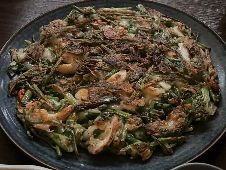 대구광역시 수성구 요리주점 한식주점 새롬 대구 다찌석에 놓인 바삭한 해물 미나리전. 어두운 조명 아래 혼술을 위해 차려진 1인석 풍경.