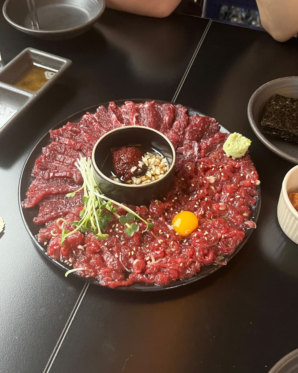 대구광역시 북구 새로나 대구 1인 다찌석 혼술. 선홍빛 생고기와 계란 노른자, 양념장이 어두운 조명 아래 테이블에 차려진 기타 메뉴 구성의 모습.
