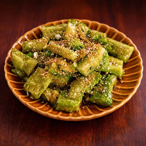 인천광역시 연수구 로바타키요 송도본점 인천 이자카야 다찌석 혼술 메뉴 오이 탕탕이. 나무 테이블 위 갈색 접시에 담긴 아삭한 오이와 깨의 질감을 조명이 비추는 상황.